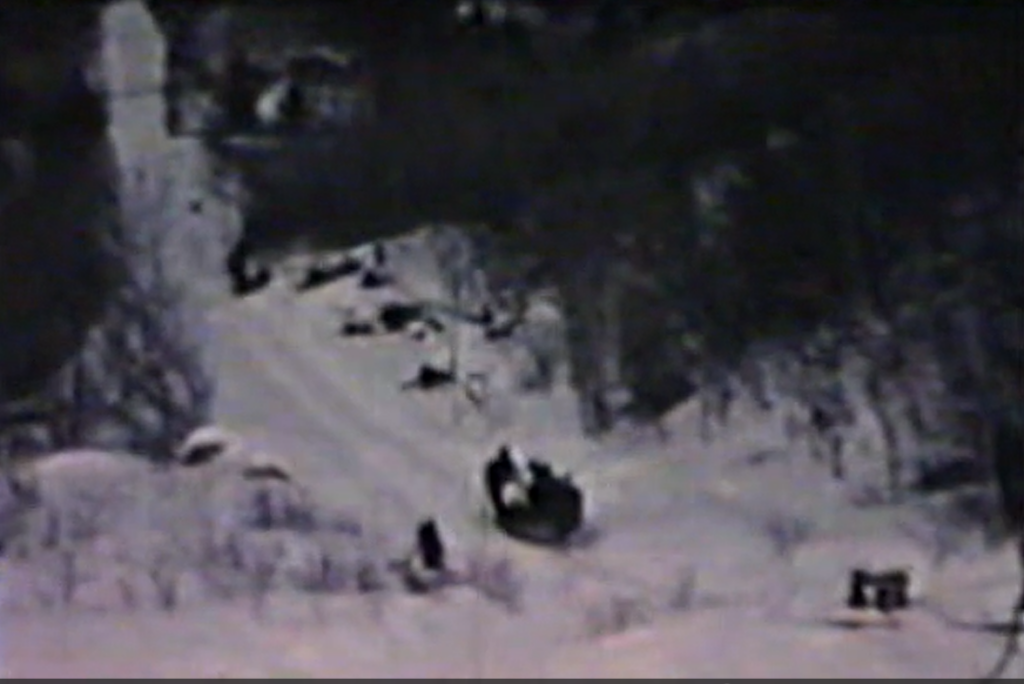 Image of a toboggan sled with passengers pulling people up a chute with their skis.